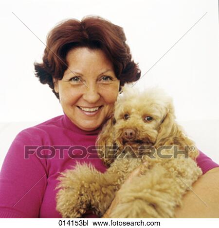 Stock Image - portrait of mature woman hugging her poodle. Fotosearch