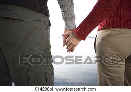 Stock Image - rear view of couple holding hands. Fotosearch