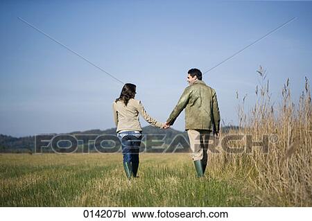 Stock Image - rear view of couple walking through autumn landscape. Fotosearch
