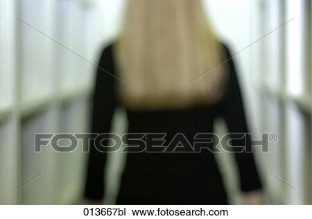 Stock Image - rear view of woman between shelves. Fotosearch