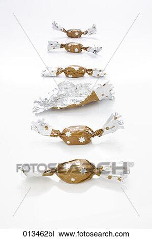 Stock Image - six sweets lying in a row one unwrapped. Fotosearch