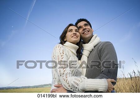 Stock Image - smiling couple looking up to the sky. Fotosearch