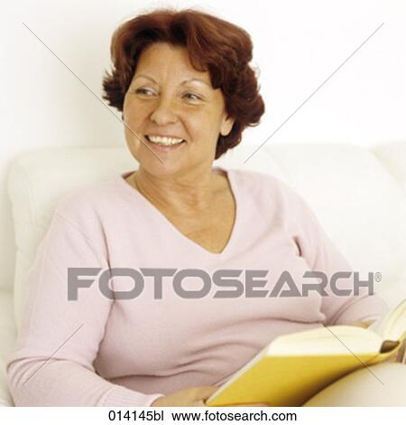 smiling woman sitting on sofa with book View Large Photo Image Stock Image - smiling woman sitting on sofa with book. Fotosearch
