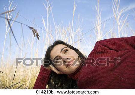 Stock Image - wistfully looking young woman lying in reeds. Fotosearch
