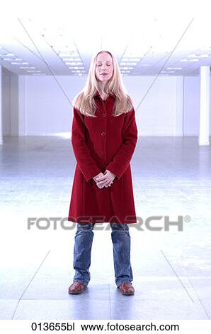 Stock Image - woman standing in office building with eyes closed. Fotosearch