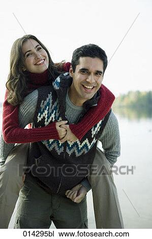 Stock Image - young couple looking at camera while playing piggyback. Fotosearch