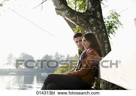young couple sitting on bench at lake talking to each other View Large Photo Image Stock Image - young couple sitting on bench at lake talking to each other. Fotosearch