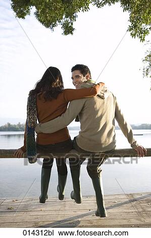 young couple sitting together man looking over his shoulder View Large Photo Image Stock Image - young couple sitting together man looking over his shoulder. Fotosearch