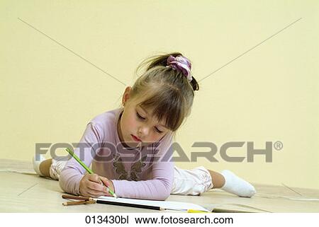 Stock Image - young girl lying on floor drawing. Fotosearch