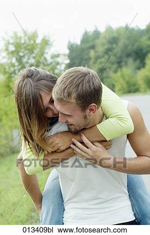 Stock Image - young man carrying his girlfriend piggyback. Fotosearch