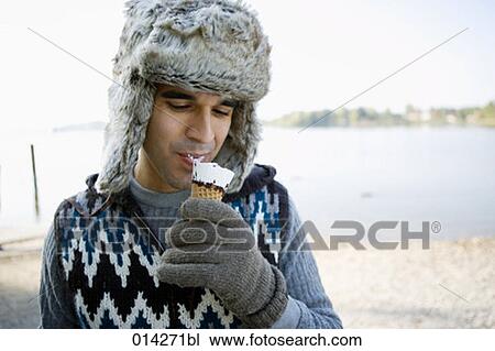 Stock Image - young man eating ice cream in winter. Fotosearch