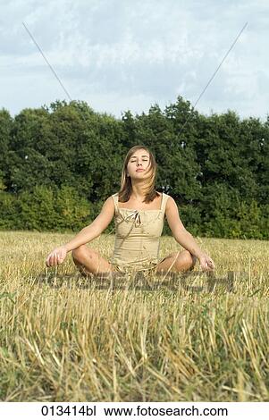 Stock Image - young woman meditating in field. Fotosearch