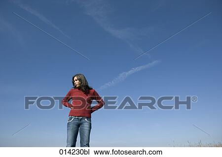 young woman standing against blue sky View Large Photo Image Stock Image - young woman standing against blue sky. Fotosearch