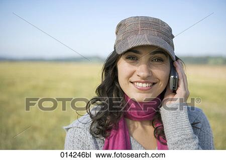 Stock Image - young woman with moblie phone looking at camera. Fotosearch
