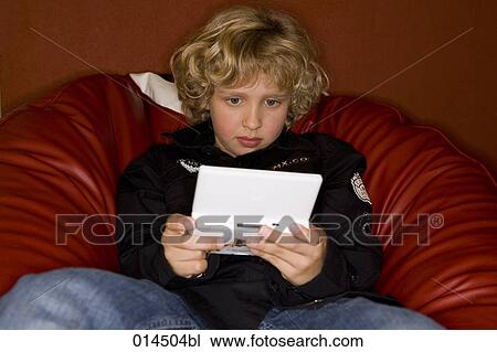 blond boy sitting in armchair playing computer game View Large Photo Image Stock Image - blond boy sitting in armchair playing computer game. Fotosearch