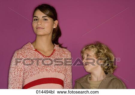 Stock Image - blonde boy looking at his older sister. Fotosearch