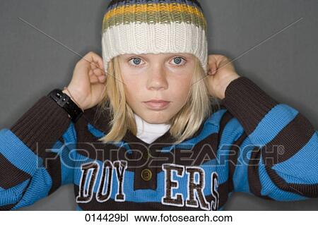 Stock Image - boy putting on winter hat. Fotosearch