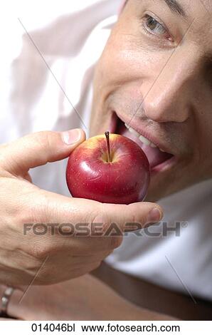 Stock Image - close-up of man biting in red apple. Fotosearch