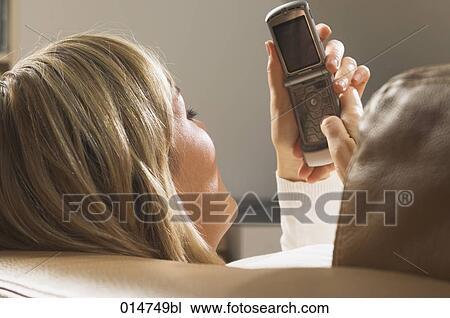 close-up of young woman on sofa checking her mobile phone for text messages View Large Photo Image Stock Image - close-up of young woman on sofa checking her mobile phone for text messages. Fotosearch