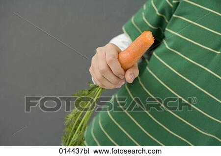detail of boy in green shirt holding carrot in hand View Large Photo Image Stock Image - detail of boy in green shirt holding carrot in hand. Fotosearch