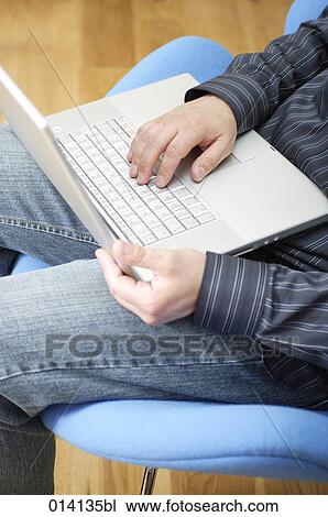 detail of man sitting in lounge chair typing on notebook computer View Large Photo Image Stock Image - detail of man sitting in lounge chair typing on notebook computer. Fotosearch