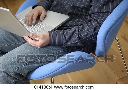 detail of man sitting in lounge chair typing on notebook computer View Large Photo Image Stock Image - detail of man sitting in lounge chair typing on notebook computer. Fotosearch