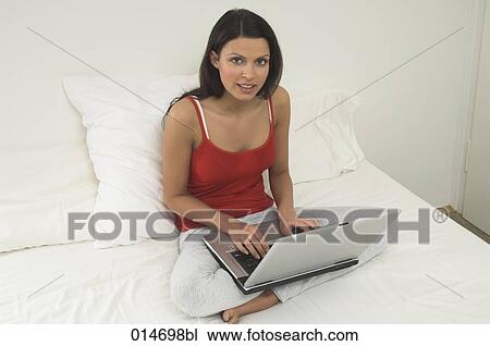 full body portrait of young woman sitting on bed and working with laptop computer View Large Photo Image Stock Image - full body portrait of young woman sitting on bed and working with laptop computer. Fotosearch