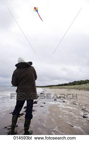 Stock Image - full boy portrait of man playing with kite on beach in autumn. Fotosearch