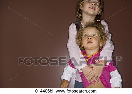 Stock Image - girl holding her astonished looking little sister. Fotosearch