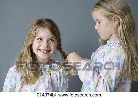 girl plaiting hair of younger sistes View Large Photo Image Stock Image - girl plaiting hair of younger sistes. Fotosearch