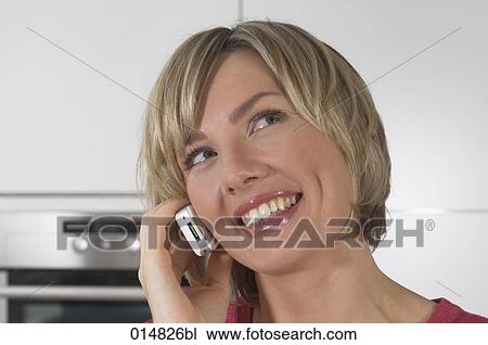 headshot of smiling young woman with cellphone in kitchen View Large Photo Image Stock Image - headshot of smiling young woman with cellphone in kitchen. Fotosearch