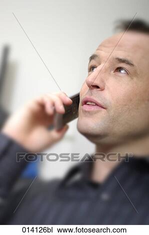 Stock Image - headshot of young businessman on mobile phone. Fotosearch