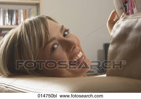 headshot of young woman on sofa reading magazine View Large Photo Image Stock Image - headshot of young woman on sofa reading magazine. Fotosearch