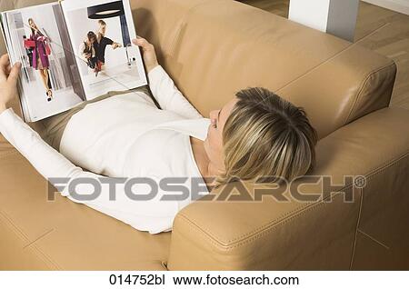 high angle view of young woman relaxing on leather sofa reading magazine View Large Photo Image Stock Image - high angle view of young woman relaxing on leather sofa reading magazine. Fotosearch