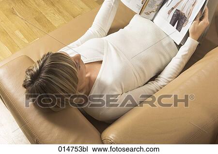 high angle view of young woman relaxing on leather sofa reading magazine View Large Photo Image Stock Image - high angle view of young woman relaxing on leather sofa reading magazine. Fotosearch