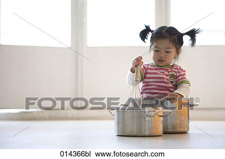 Stock Image - little asian girl playing with pots. Fotosearch