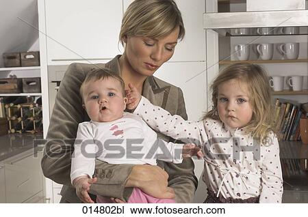 little girl touching her younger sister held by her mother View Large Photo Image Stock Image - little girl touching her younger sister held by her mother. Fotosearch