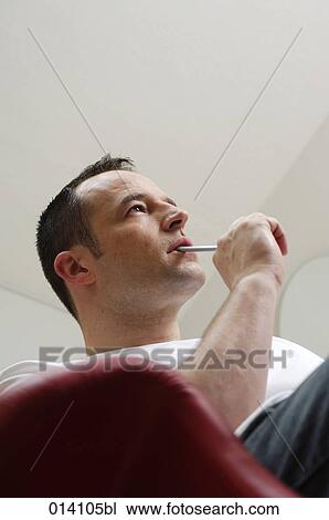 low angle portrait of young man with pen in mouth thinking View Large Photo Image Stock Image - low angle portrait of young man with pen in mouth thinking. Fotosearch