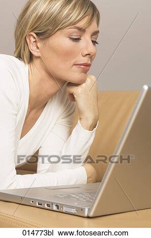 Stock Image - portrait of blonde woman looking at screen of notebook computer. Fotosearch