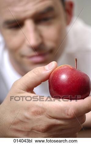 Stock Image - portrait of man looking at red apple. Fotosearch