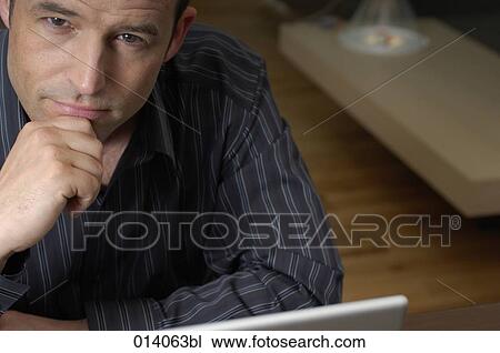 portrait of man sitting at laptop computer in living room View Large Photo Image Stock Image - portrait of man sitting at laptop computer in living room. Fotosearch
