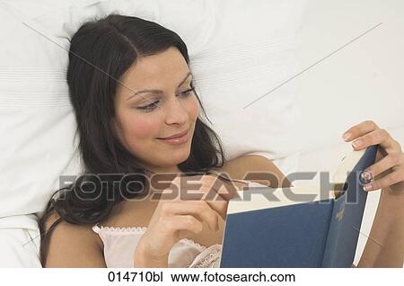 portrait of smiling young woman reading book in bed View Large Photo Image Stock Image - portrait of smiling young woman reading book in bed. Fotosearch