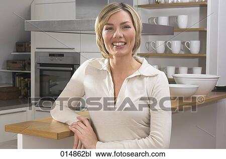 portrait of smiling young woman standing in kitchen View Large Photo Image Stock Image - portrait of smiling young woman standing in kitchen. Fotosearch