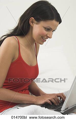 Stock Image - portrait of smiling young woman working with laptop computer. Fotosearch