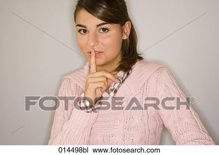 Stock Image - portrait of teenager holding finger before mouth to keep a secret. Fotosearch