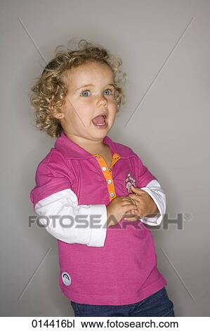 Stock Image - portrait of toddler with curls standing with mouth open. Fotosearch