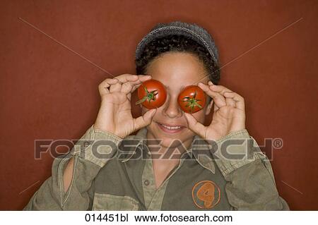 Stock Image - portrait of young boy covering his eyes with tomatoes. Fotosearch