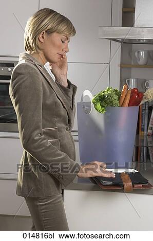 portrait of young businesswoman standing in kitchen, talking on mobile phone and looking at her diary View Large Photo Image Stock Image - portrait of young businesswoman standing in kitchen, talking on mobile phone and looking at her diary. Fotosearch
