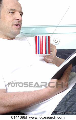 portrait of young man relaxing with cup of coffee or tea and book on sofa View Large Photo Image Stock Image - portrait of young man relaxing with cup of coffee or tea and book on sofa. Fotosearch