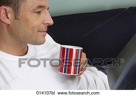 portrait of young man relaxing with book and coffee cup on sofa View Large Photo Image Stock Image - portrait of young man relaxing with book and coffee cup on sofa. Fotosearch
